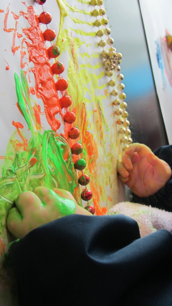 Both of Eli's hands are busy in the paint and holding the beads and rings
